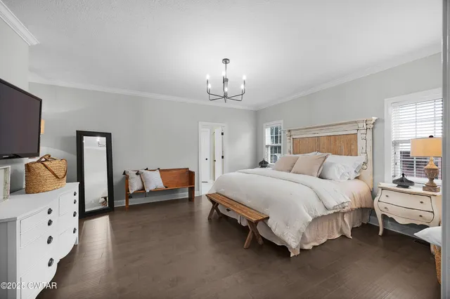 a spacious bedroom with a bed and a flat tv screen on the dresser