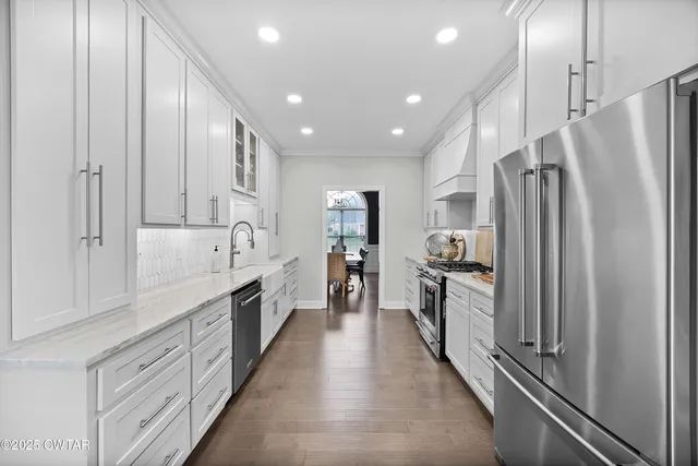 a large kitchen with cabinets a sink and stainless steel appliances
