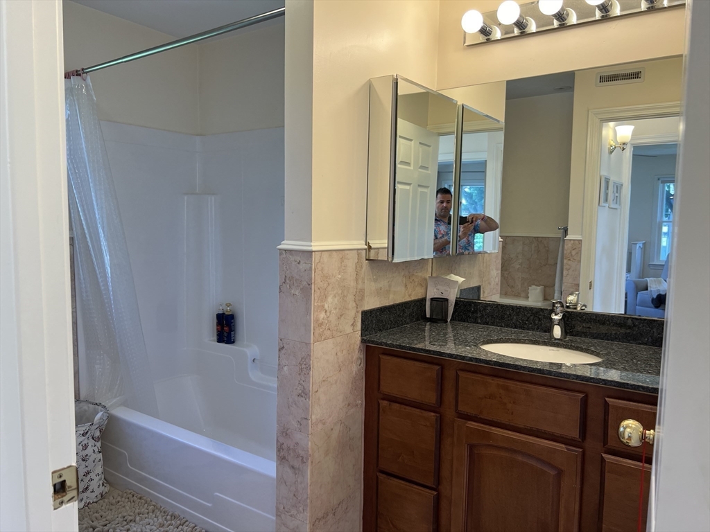 11 Garrison Road, Unit 1 Arlington, MA 02474 - Photo 36 of 42 a bathroom with a granite countertop sink a mirror and a bathtub