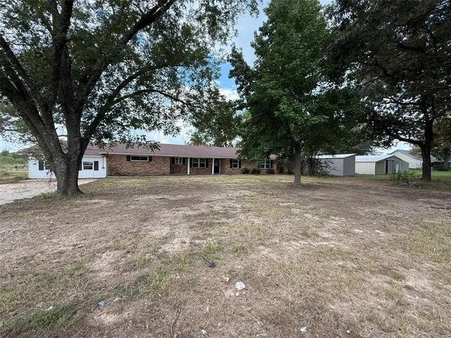 a front view of a house with large trees