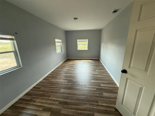 a view of an empty room with wooden floor and window