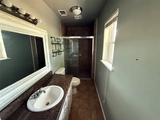 a bathroom with a sink a toilet a mirror and shower
