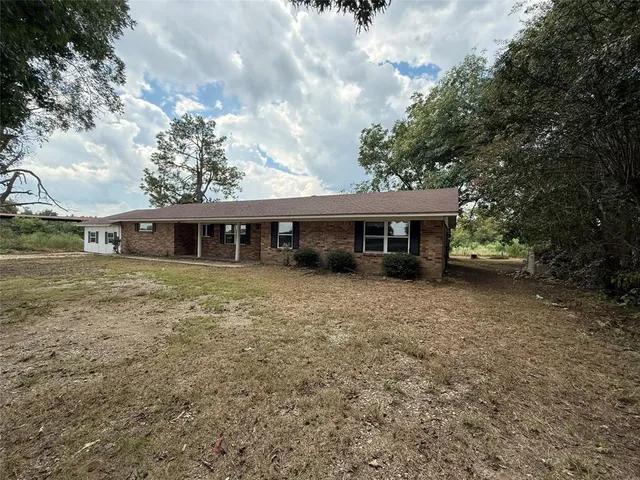 a front view of a house with a garden and trees