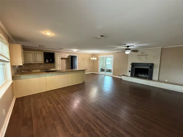 a large kitchen with granite countertop a stove top oven a sink dishwasher and a fireplace with wooden floor
