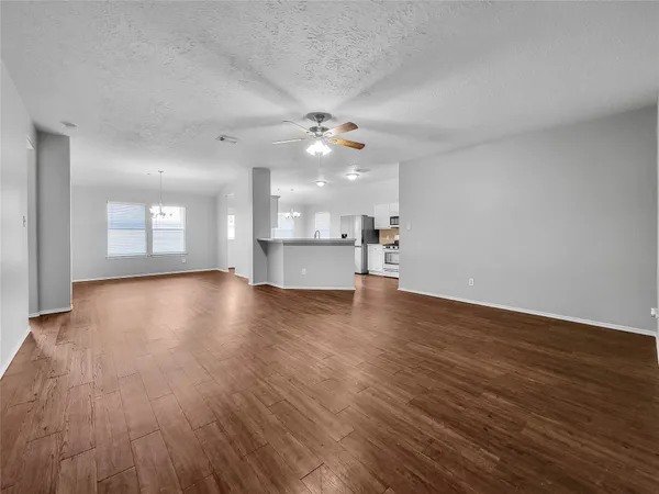 a view of a kitchen and an empty room with a window