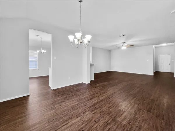 a view of a livingroom with a chandelier fan and wooden floor