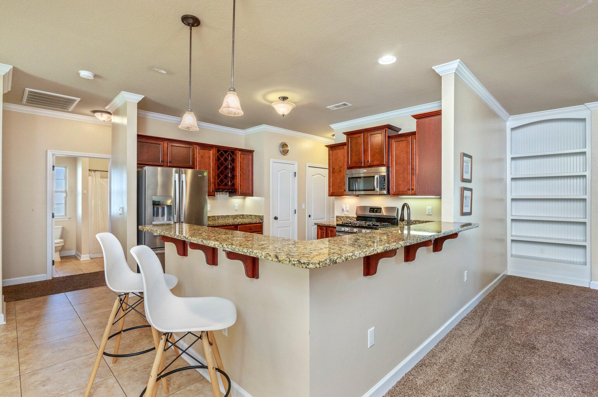4615 Chanan Drive Crestview, FL 32539 - Photo 15 of 47 a kitchen with stainless steel appliances kitchen island granite countertop a stove a refrigerator a sink a dining table and chairs with wooden floor