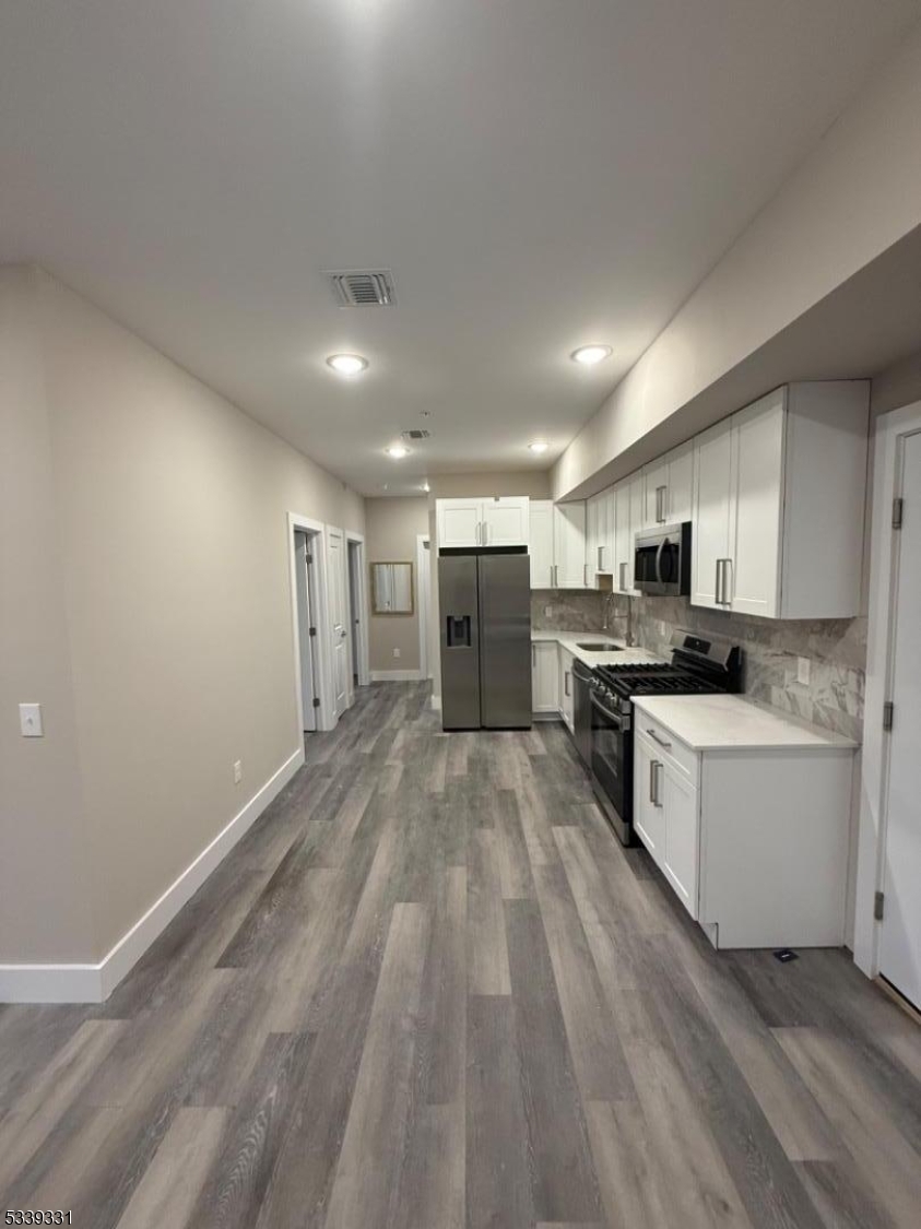 a large white kitchen with stainless steel appliances granite countertop a stove and a refrigerator
