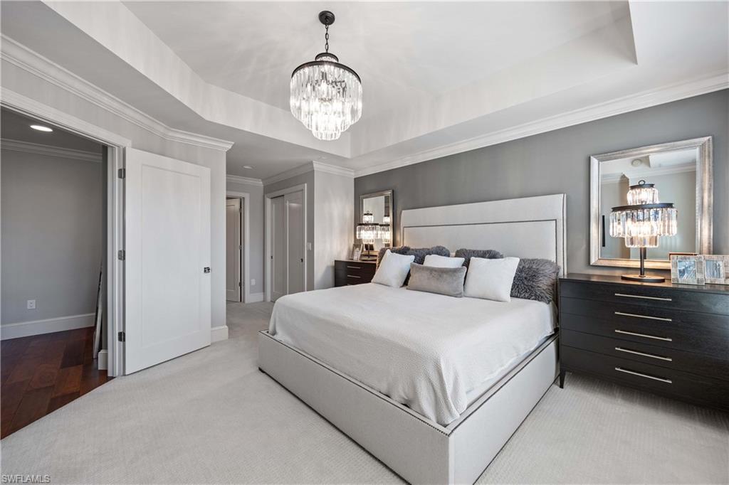 9123 Strada Place, Unit 7404 Naples, FL 34108 - Photo 12 of 36 a bedroom with a large bed and a chandelier