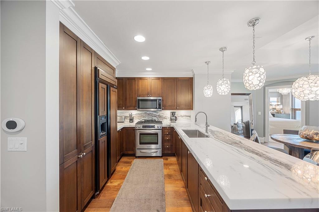 9123 Strada Place, Unit 7404 Naples, FL 34108 - Photo 8 of 36 a large kitchen with stainless steel appliances kitchen island granite countertop a refrigerator a stove and a sink with granite countertops