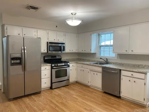 a kitchen with granite countertop a refrigerator and a stove top oven