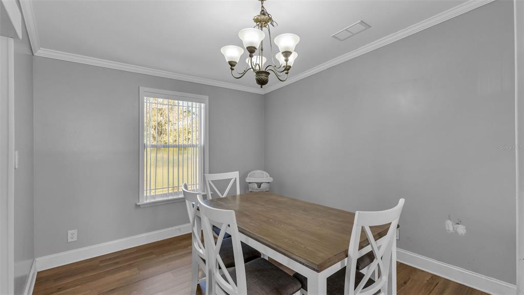7549 Sinkhole Road Bartow, FL 33830 - Photo 21 of 40 a view of a dining room with furniture a chandelier and wooden floor