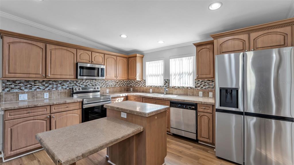 7549 Sinkhole Road Bartow, FL 33830 - Photo 23 of 40 a kitchen with a refrigerator a sink cabinets and wooden floor