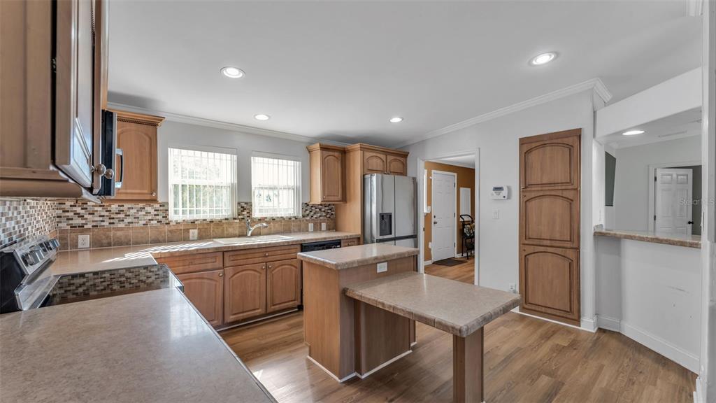 7549 Sinkhole Road Bartow, FL 33830 - Photo 26 of 40 a large kitchen with stainless steel appliances granite countertop a refrigerator a sink dishwasher a dining table and chairs with wooden floor