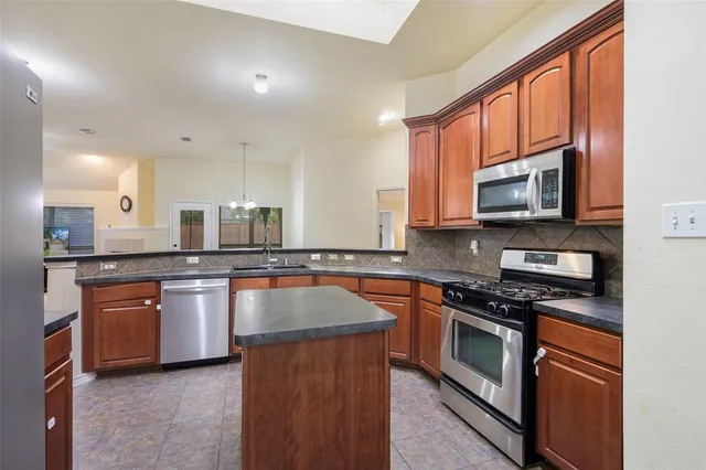 a kitchen with stainless steel appliances granite countertop a stove top oven a sink dishwasher a dining table and chairs with wooden floor