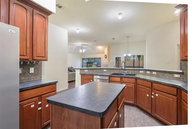 a kitchen with stainless steel appliances granite countertop a sink a stove top oven a counter space and cabinets