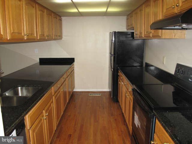 11034 Saffold Way Reston, VA 20190 - Photo 5 of 18 a kitchen with granite countertop a refrigerator a stove and wooden cabinets