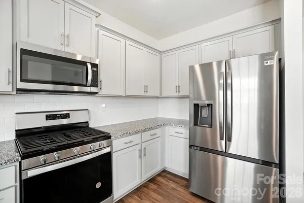 a kitchen with cabinets stainless steel appliances and wooden floor