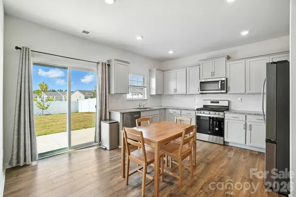 a kitchen with stainless steel appliances granite countertop a stove top oven a sink and a refrigerator