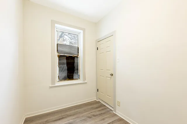 a view of a hallway with wooden floor and a bathroom