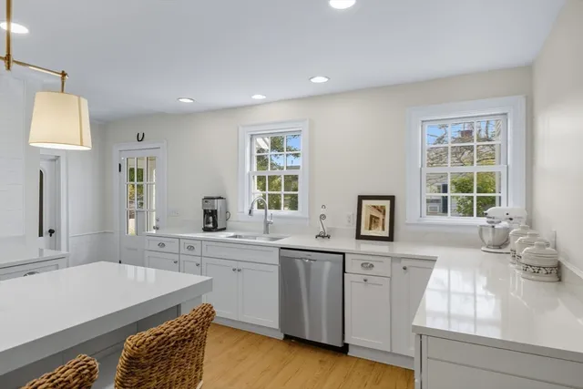 a large white kitchen with a sink wooden floor and a window
