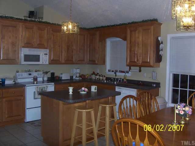 875 Bill Avery Road Coats, NC 27521 - Photo 4 of 8 a kitchen with granite countertop a stove a sink a counter space and cabinets