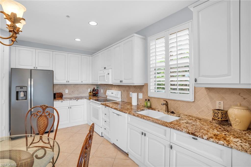 9006 Cascada Way, Unit 101 Naples, FL 34114 - Photo 11 of 25 a kitchen with granite countertop a sink appliances cabinets and a counter top space