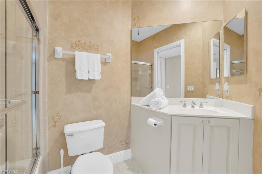 9006 Cascada Way, Unit 101 Naples, FL 34114 - Photo 20 of 25 a bathroom with a toilet sink and mirror