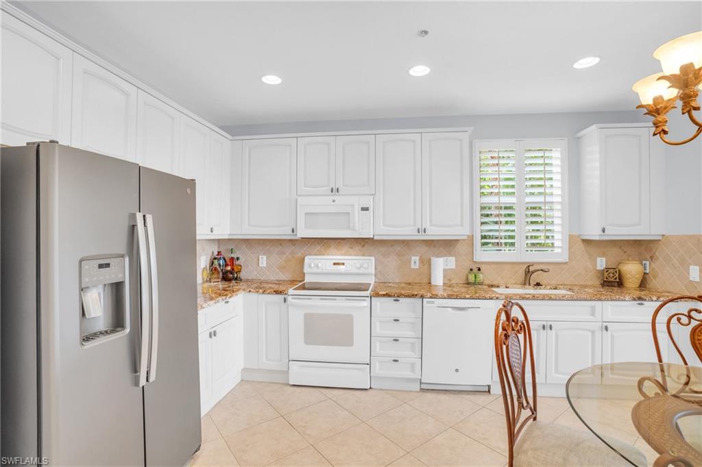 9006 Cascada Way, Unit 101 Naples, FL 34114 - Photo 10 of 25 a kitchen with stainless steel appliances granite countertop a refrigerator sink and cabinets