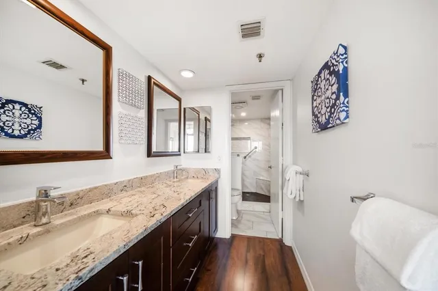 a bathroom with a granite countertop double vanity sink and mirror