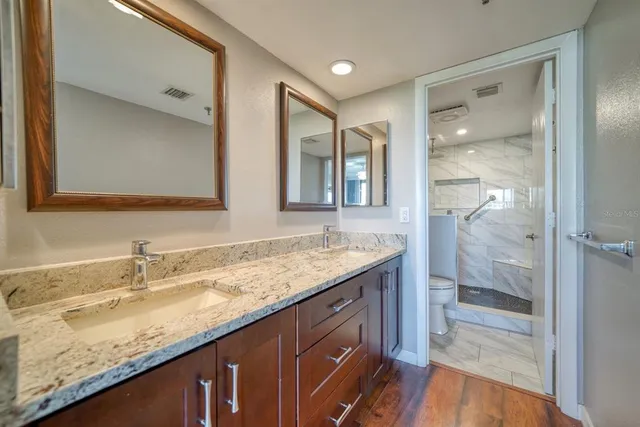 a bathroom with a granite countertop sink a mirror and a shower