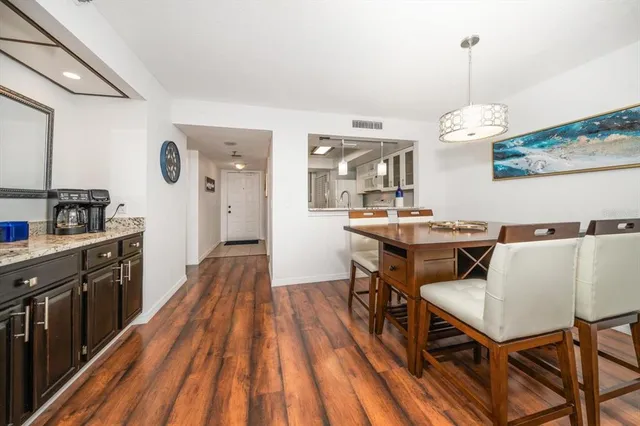 a dining room with wooden floor and kitchen