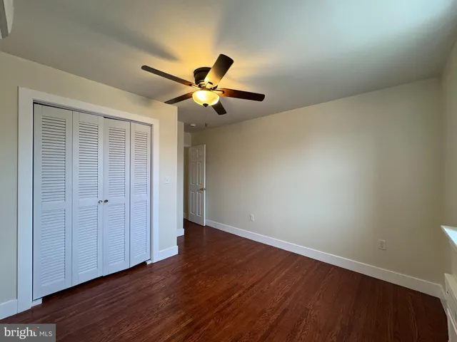 an empty room with wooden floor and a ceiling fan