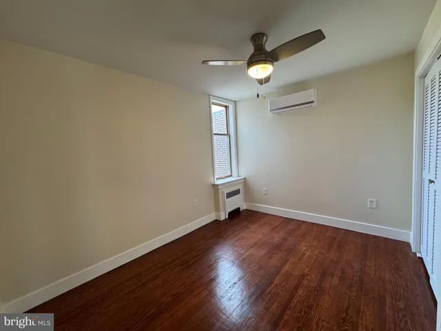 an empty room with wooden floor fan and windows