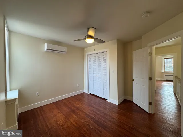 a bedroom with wooden floor closet and windows
