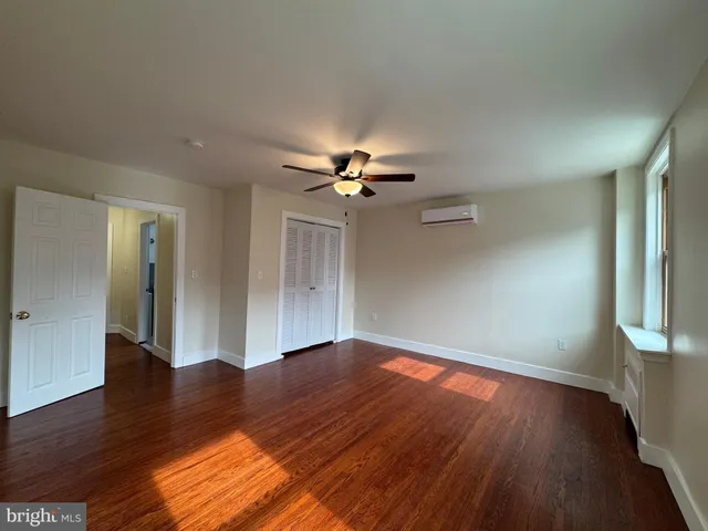a view of a livingroom with wooden floor a ceiling fan and a window