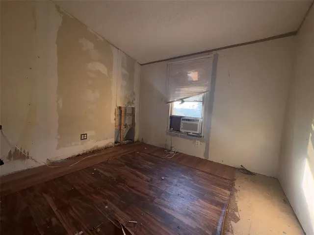 a view of an empty room with window and wooden floor