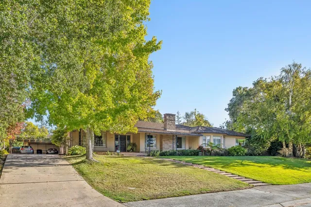 a view of a white house with a big yard and large trees