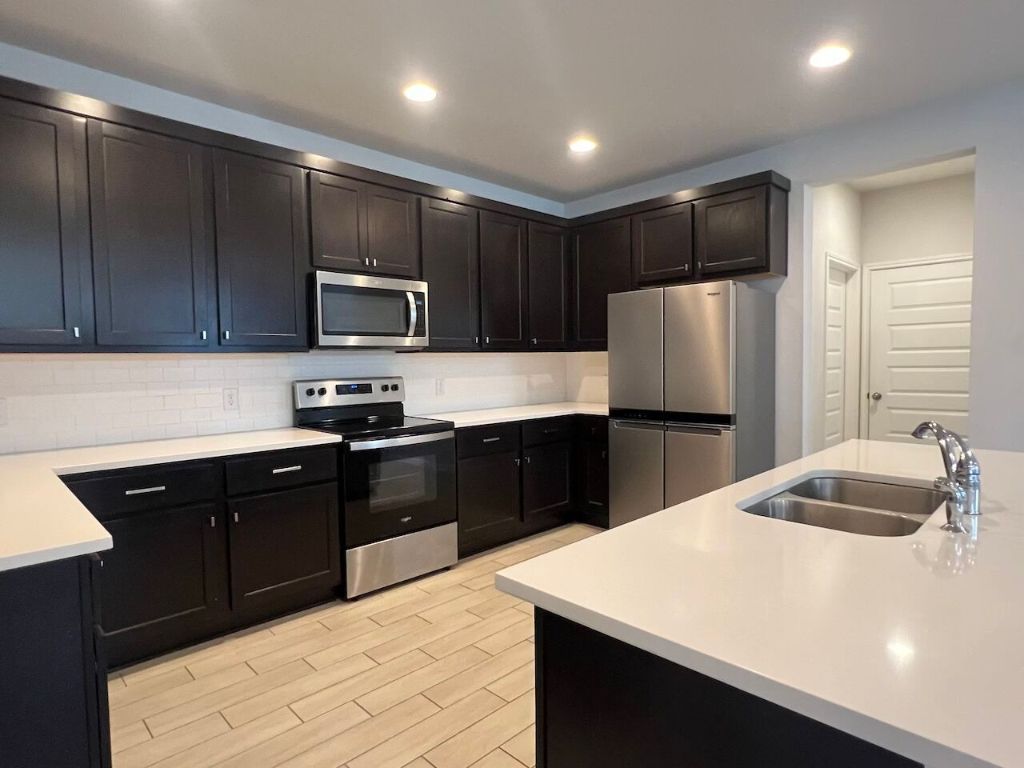 124 Old Stagecoach Road Jarrell, TX 76537 - Photo 10 of 40 a kitchen with kitchen island a refrigerator a sink a stove a microwave and wooden cabinets