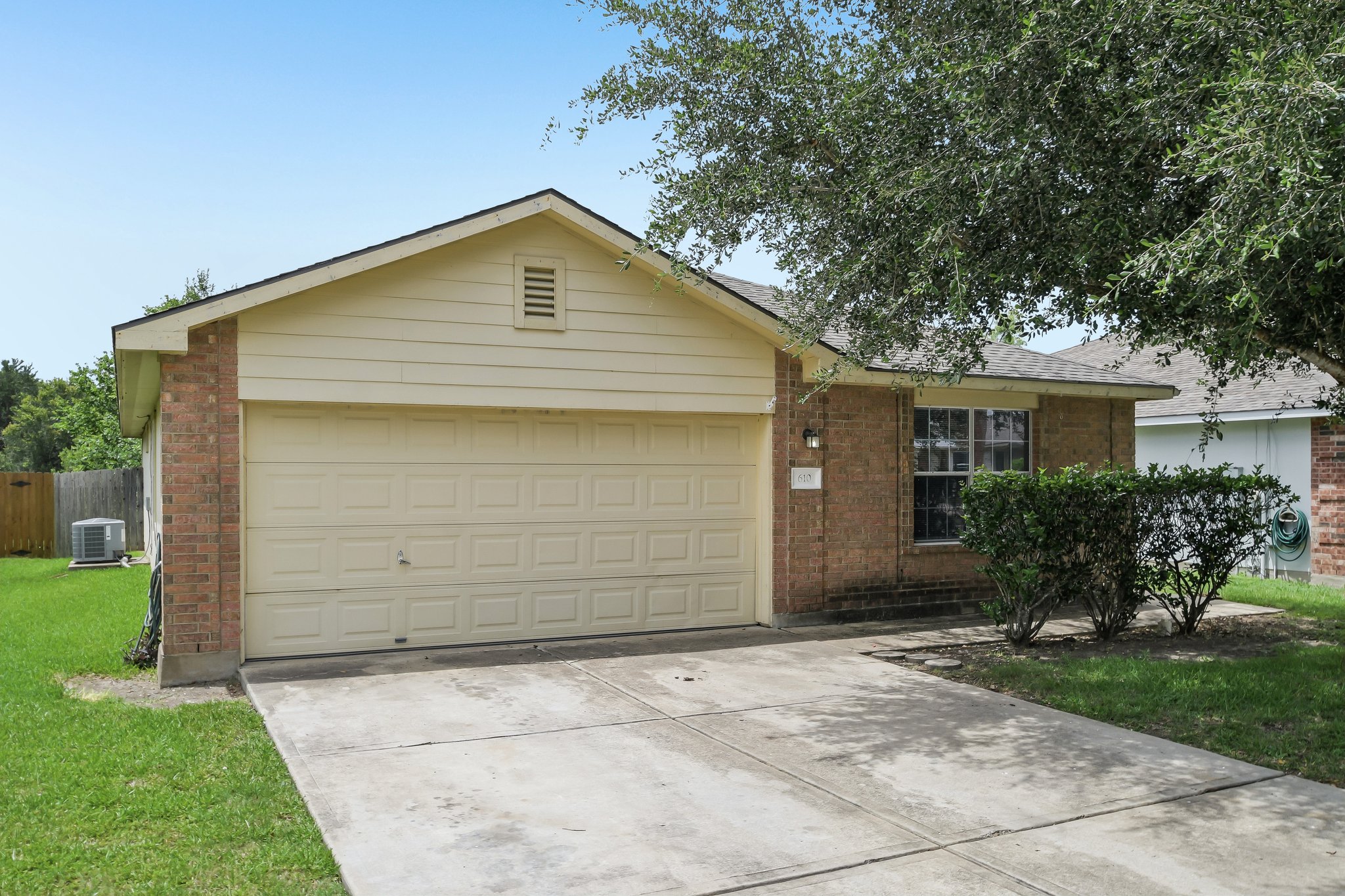 610 Lavaca Loop Elgin, TX 78621 - Photo 2 of 37 A classic brick and siding home features a two-car garage and a well-kept front yard with mature landscaping.