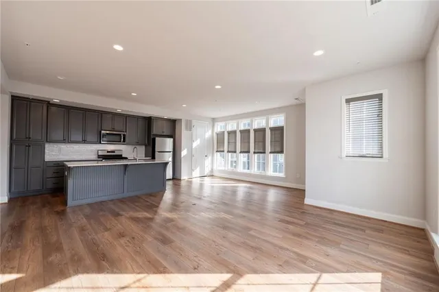 a large kitchen with stainless steel appliances granite countertop a large counter top and wooden floors