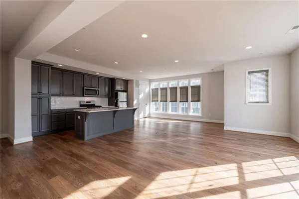 a large kitchen with kitchen island a sink wooden floor and stainless steel appliances