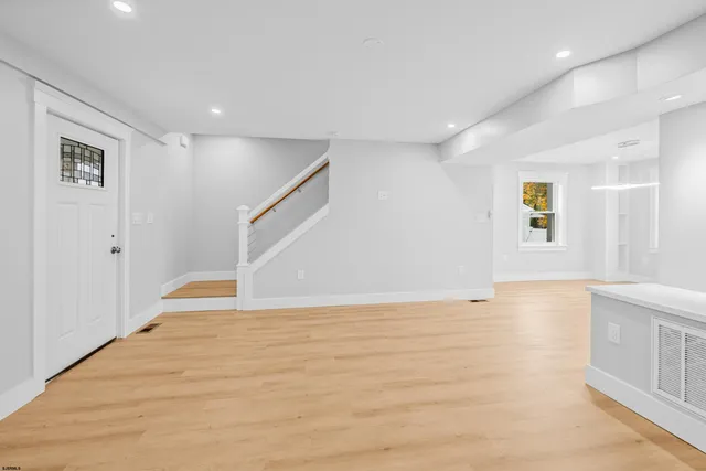 a view of an empty room with window and wooden floor