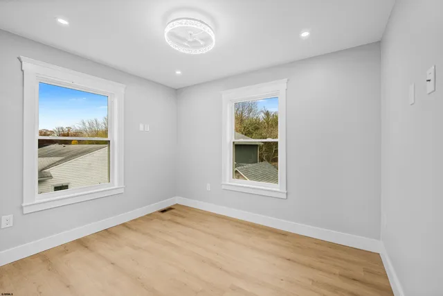 a view of empty room with window and wooden floor