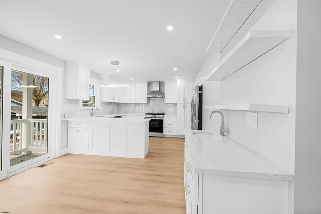 a large white kitchen with a refrigerator a stove top oven and a sink