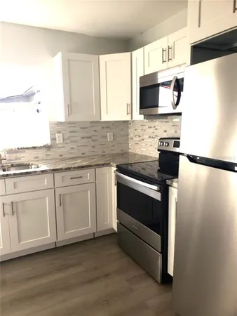 a kitchen with stainless steel appliances white cabinets and a refrigerator