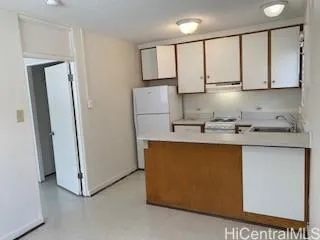 a kitchen with stainless steel appliances granite countertop a refrigerator a sink a stove and white cabinets with wooden floor