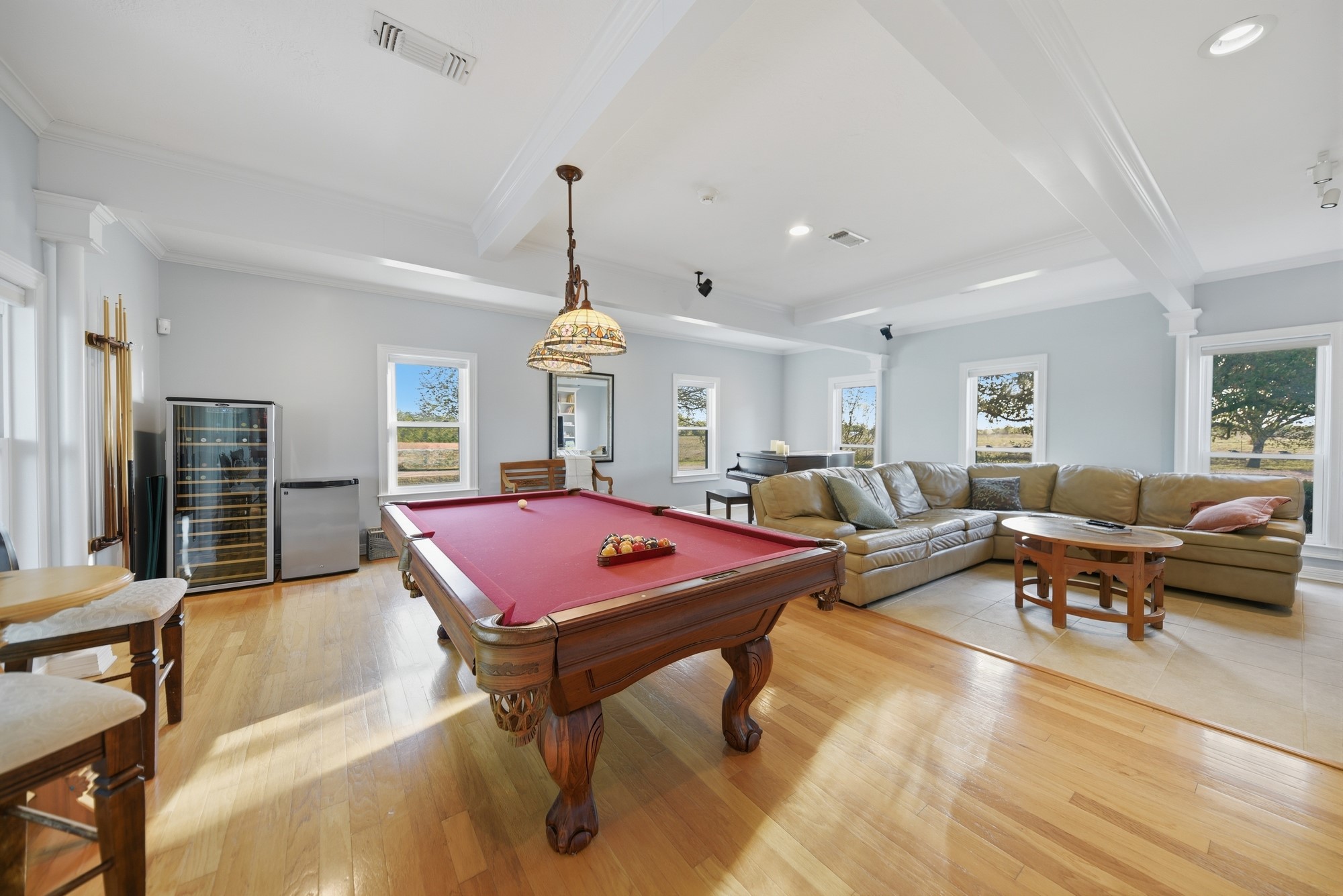 5255 Ganske Road Burton, TX 77835 - Photo 11 of 46 This spacious, light-filled entertainment room features a red-felt pool table, comfortable seating, and large windows offering scenic views. It includes a mini-fridge and bar seating, ideal for gatherings and relaxation.