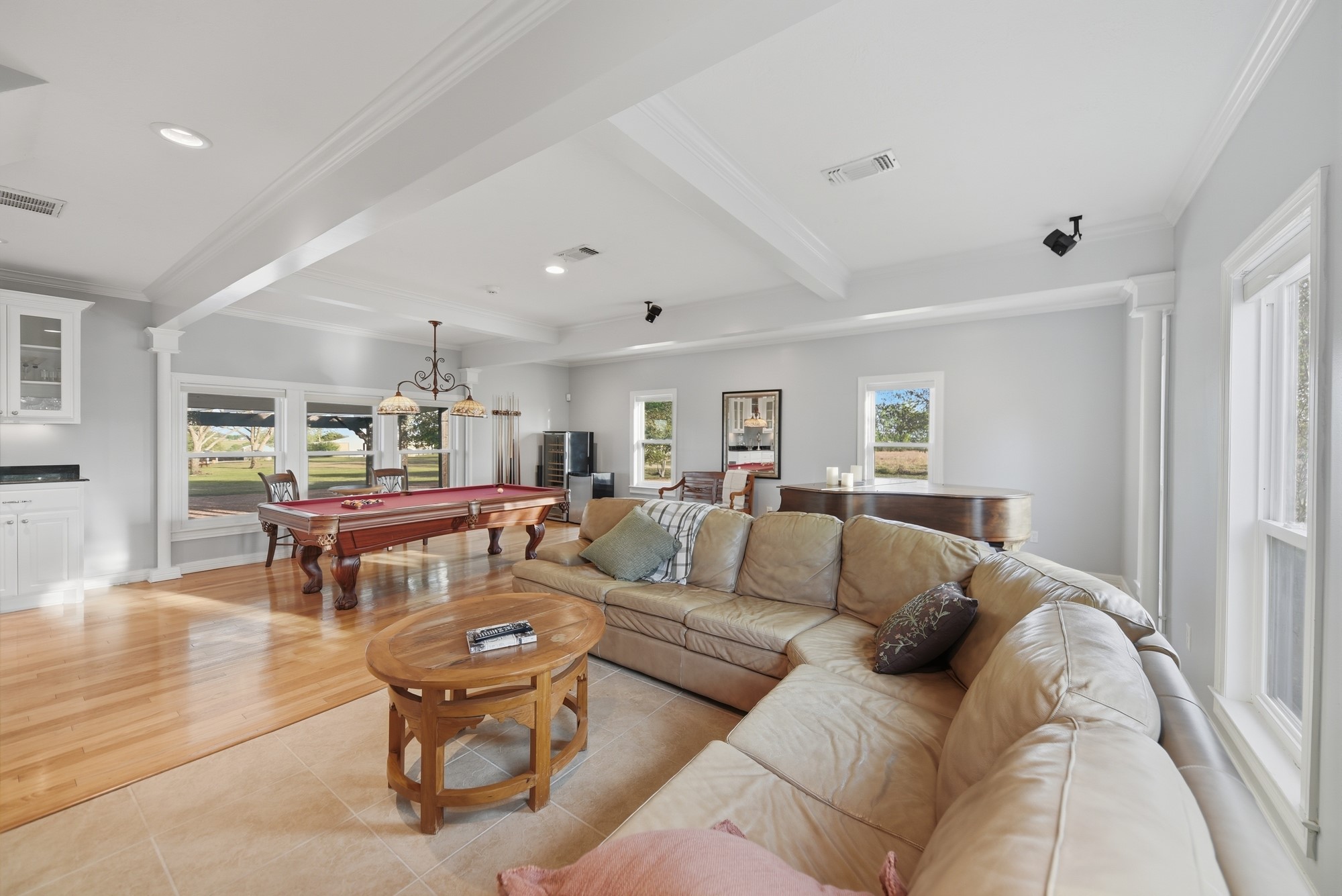 5255 Ganske Road Burton, TX 77835 - Photo 12 of 46 Open-concept living area features a large sectional sofa, a pool table, and abundant natural light from multiple windows. The hardwood floors and neutral color palette create a welcoming atmosphere, perfect for entertaining or relaxing.