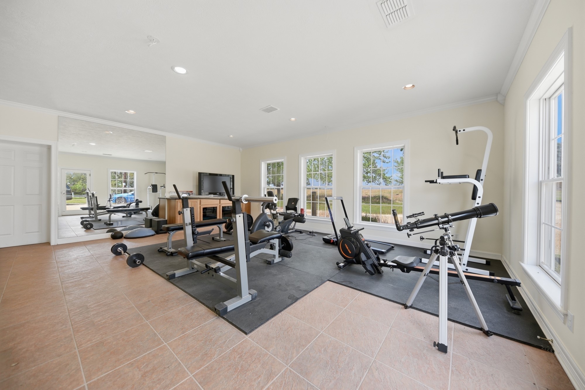 5255 Ganske Road Burton, TX 77835 - Photo 18 of 46 Inside shop...This spacious gym features large windows for natural light, a variety of exercise equipment, and a tiled floor, creating a bright and functional workout area.